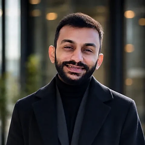 Dhrumil Shah, smiling, in a dark coat